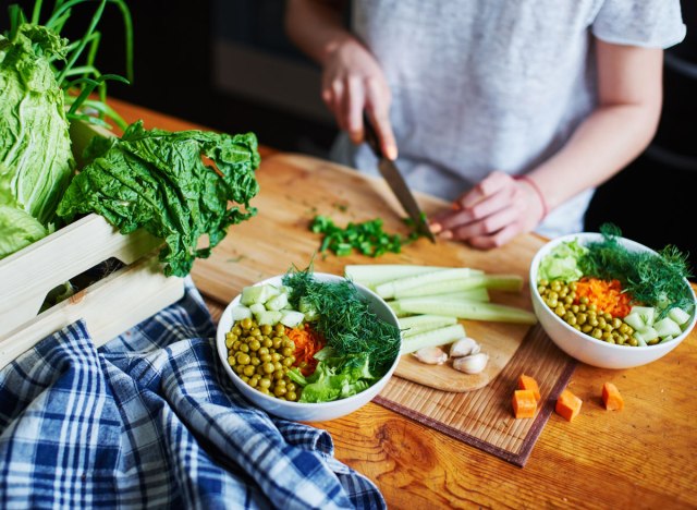 Woman chops up vegetables to make plant-based vegetarian dish