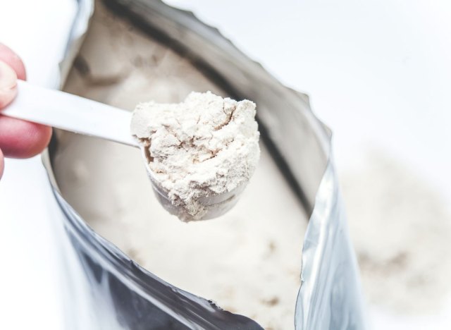 holding scoop white plain protein powder from bag