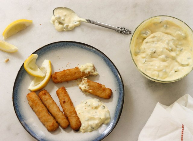 tartar sauce with fish sticks and lemon wedges on a plate