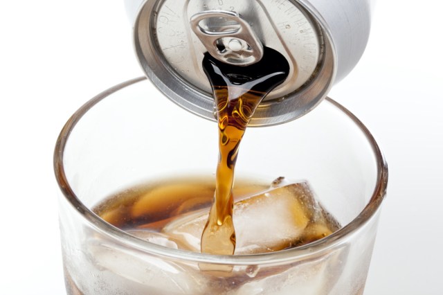 brown soda in a clear glass against a white background