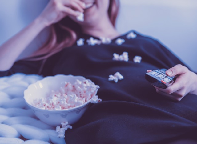 woman eating popcorn by tv