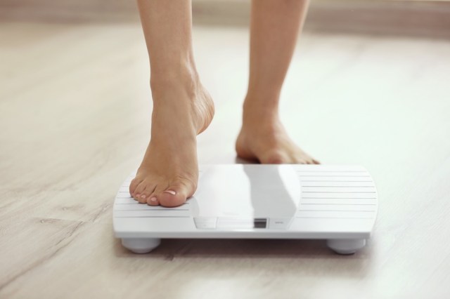 female leg stepping on floor scales