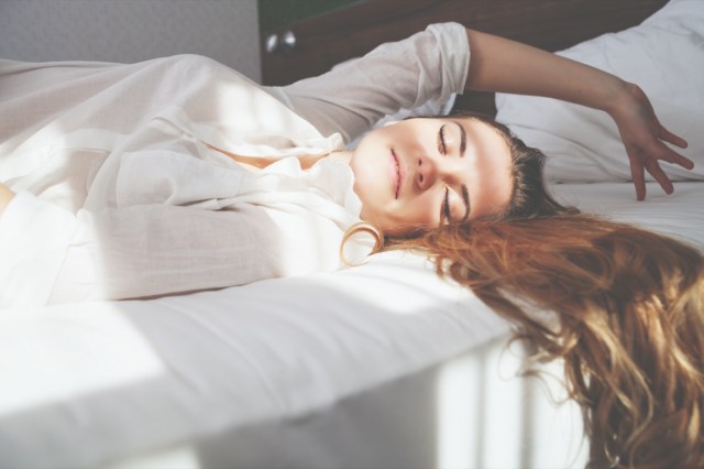 pretty young woman on bed in modern apartment smiling after wake up