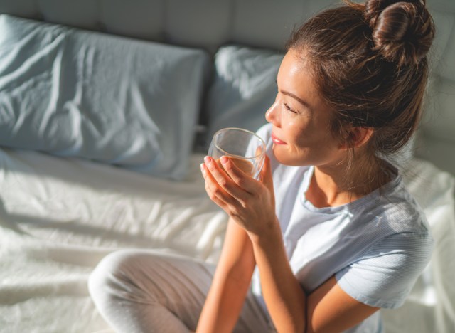 woman drinking tea and water in bed in the morning