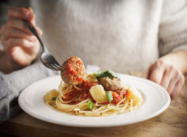 woman eating pasta meatballs for dinner