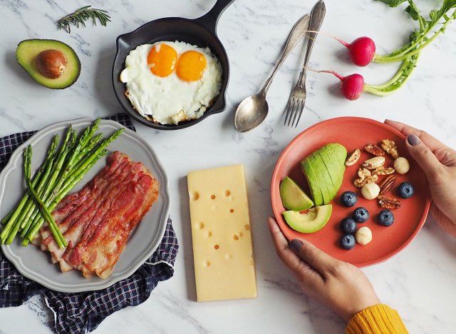 woman holding plate of keto foods at a table