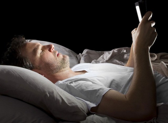 Man laying in bed on phone - how to lose weight overnight