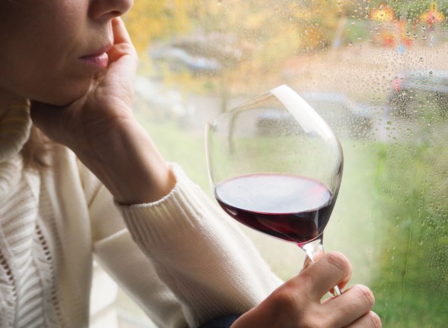 woman drinking wine by window - how to lose weight overnight