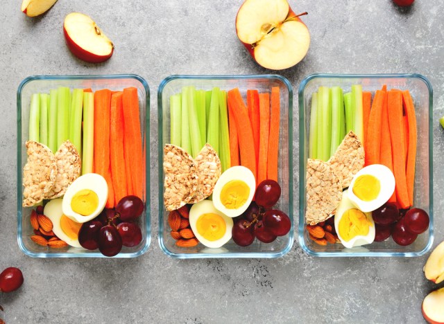 healthy snack meal prep with cut carrots celery hard boiled eggs apples grape almonds and rice cakes