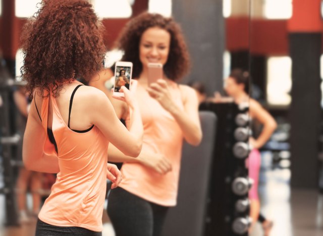 woman taking mirror selfie at a gym showing off her weight loss