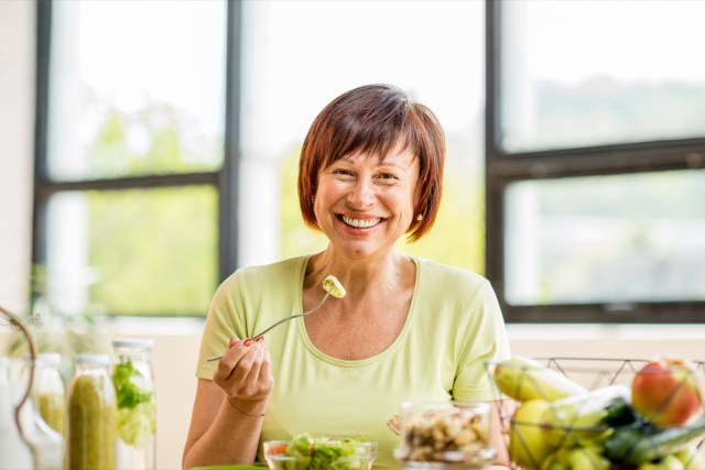 older woman with green healthy food on the table