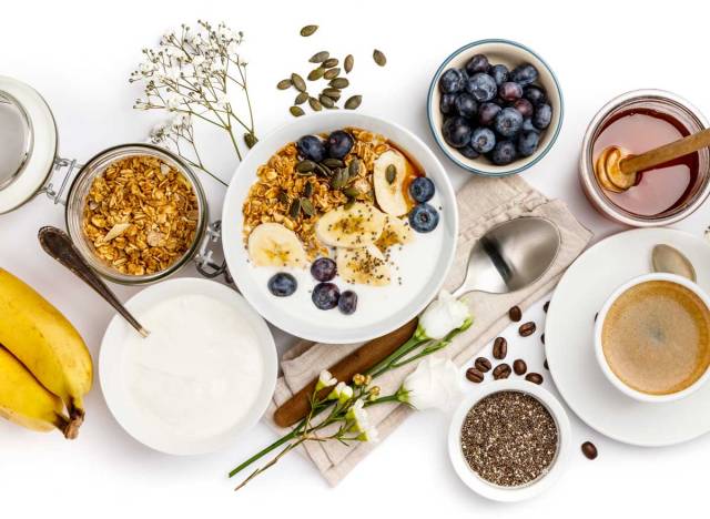 healthy breakfast foods blueberries bananas bowl of yogurt oatmeal and coffee