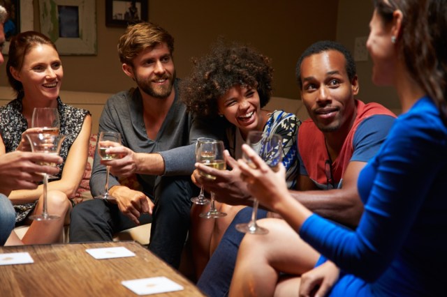 group of friends sitting around a table at the house party