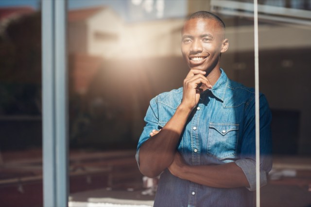 young african designer looking through window thinking about the future