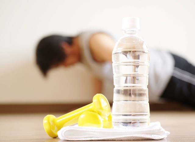 plastic water bottle with man doing push-ups in background