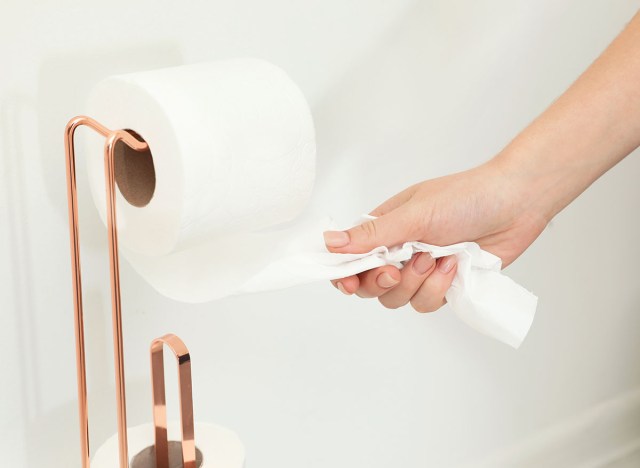 woman grabs toilet paper from roll