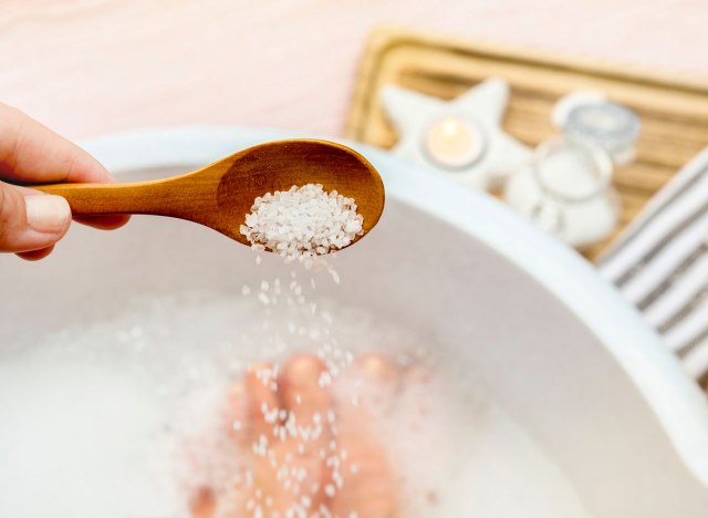 woman pouring epsom salt into the bath