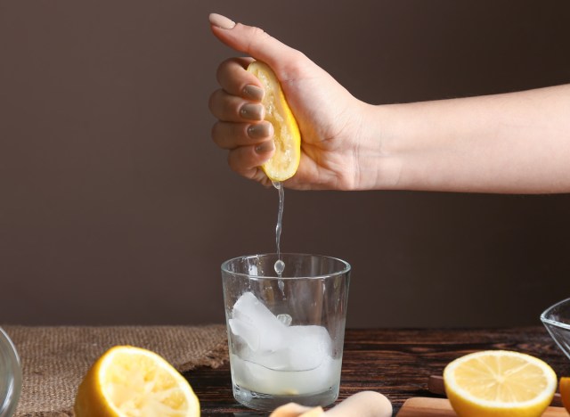 woman squeezing lemon in glass of water