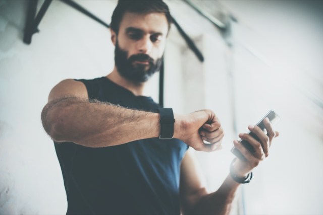 bearded sporty man after workout checks fitness results smartphone