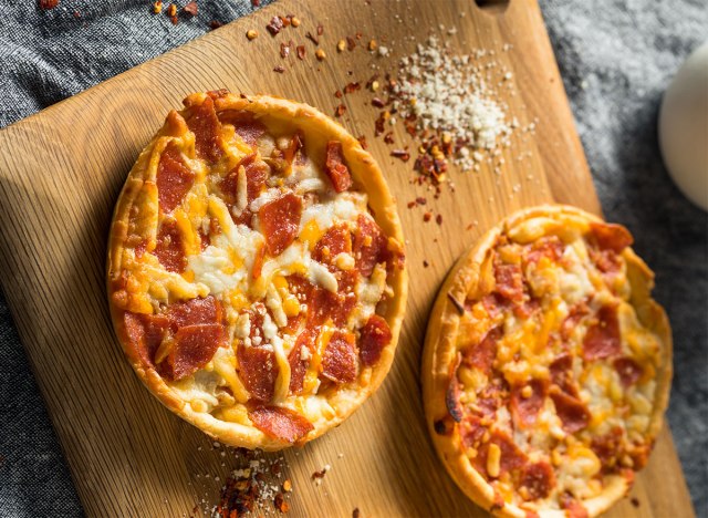 two individual frozen pizzas on a wooden board