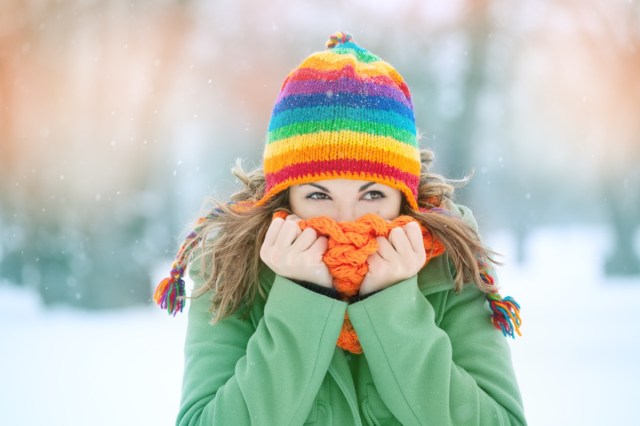 woman in snow with scarf on face trying to warm up