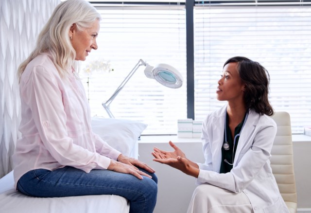 mature woman in consultation with female doctor sitting on examination couch in office