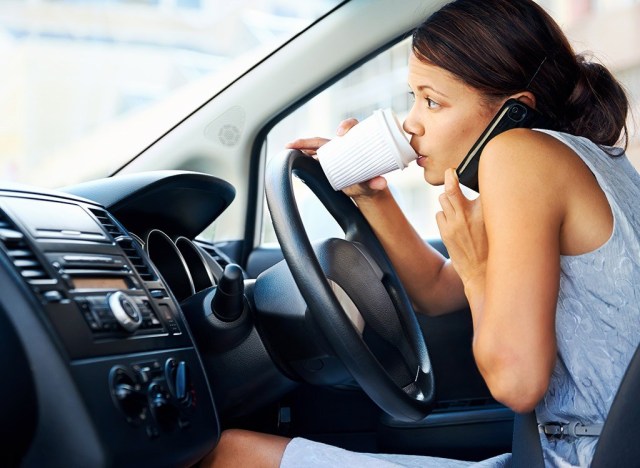 busy woman driving a car and drinking coffee