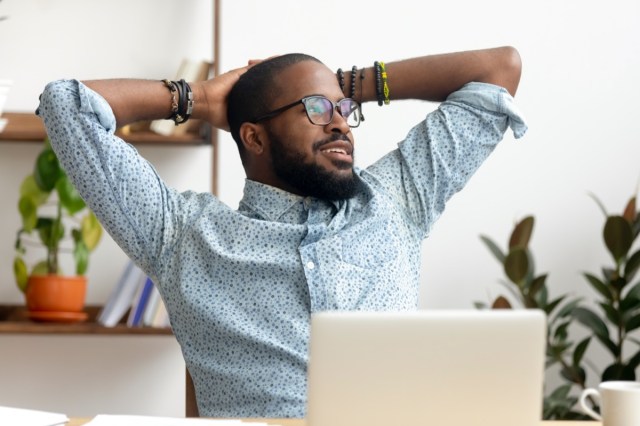 man taking a break from the workplace relaxing finished work, happy black professional employee enjoying success resting from computer feeling stress relief peace of mind sitting at desk