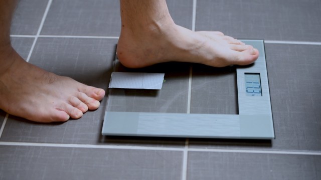 male feet on glass scales, men's diet, body weight, close-up, you step up on scales