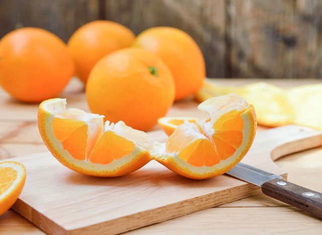 lightly peel and roll an orange on a cutting board.