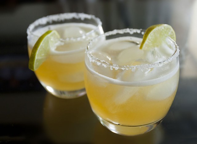 two margaritas in a glass with lime wedges