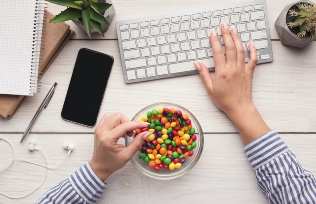 workspace with laptop, candy and woman hands