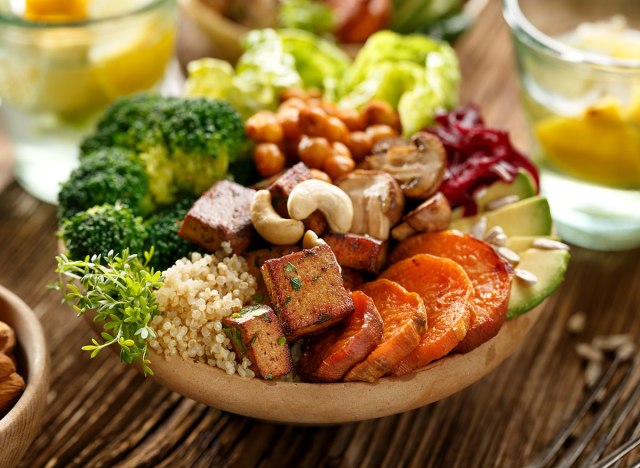 buddha bowl of plant based foods including broccoli, nuts, tofu, carrots, avocado, and much more