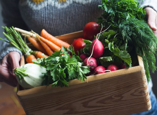 woman holding csa box with organic fresh vegetables