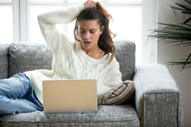 shocked young woman looking at laptop screen at home