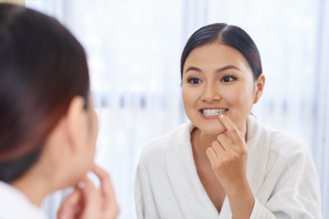 woman looking at her teeth in the mirror