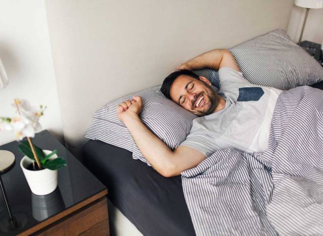 happy man waking up from sleep in bed