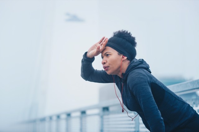 a woman taking a break from a running exercise in an outdoor urban environment.