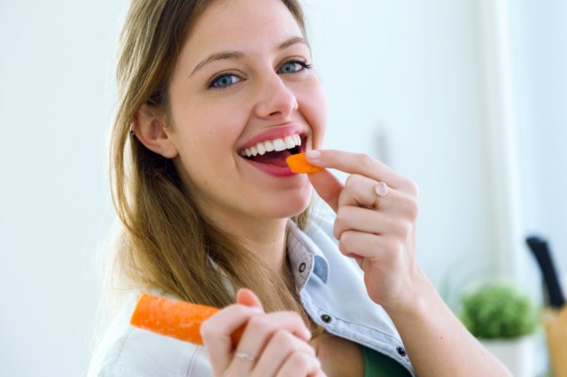 the perfect 30 second weight reduction trick, 26 woman eating carrot in the kitchen.