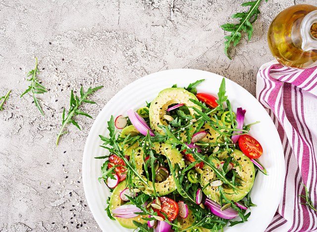 salad with tomatoes, avocado, arugula, radish, seeds on a bowl