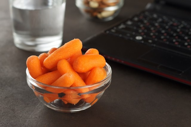 healthy snacks for office lunch: carrots, almonds, cashews and a glass of water.