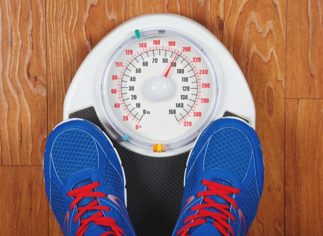 man weighing in scale with shoes on