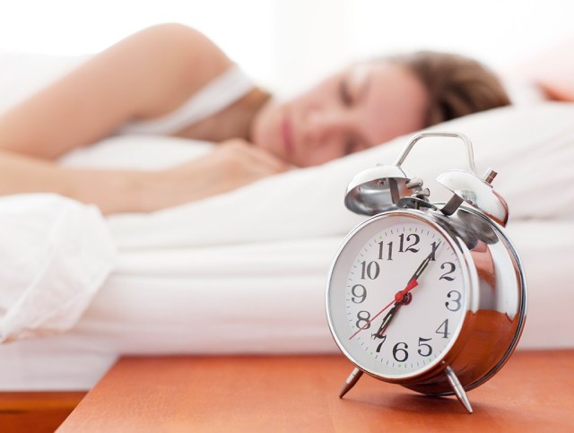 woman in bed with alarm clock