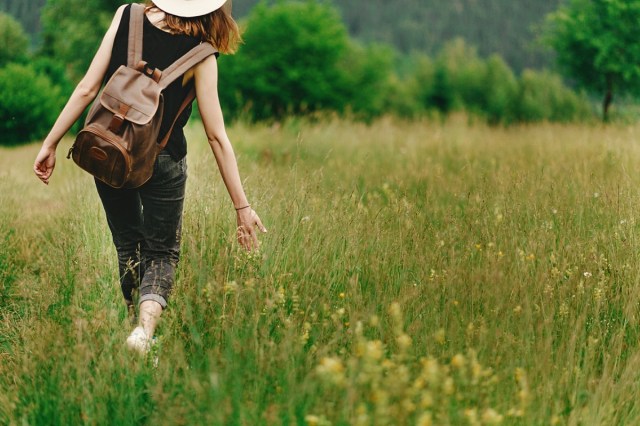 woman walking in grass and holding in hand herb flowers