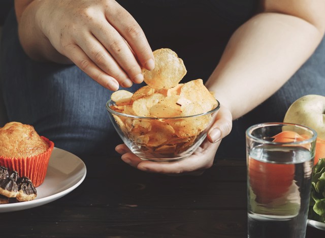 woman eating junk food on couch chips