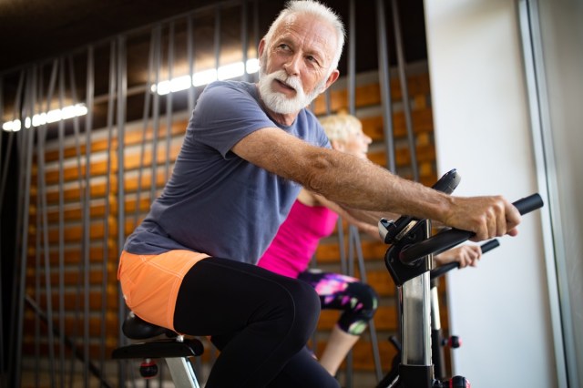 mature fit people cycling in the gym and exercising legs doing cycling training for cardio training