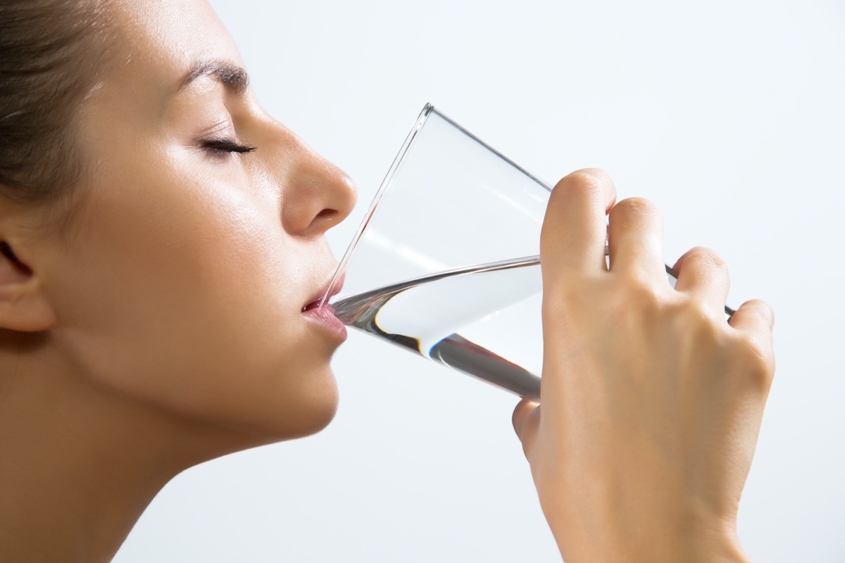 close-up of pretty young woman drinking water from glass