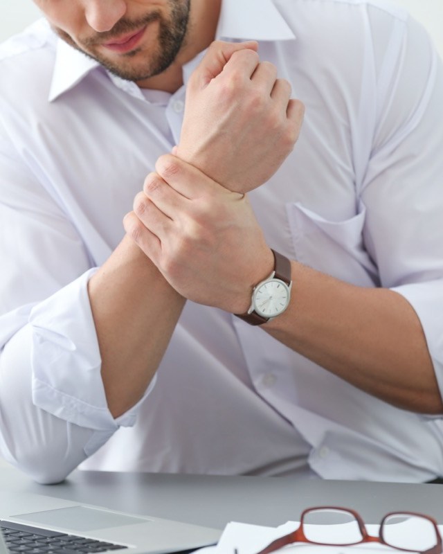 man suffering from pain in the wrist in the office