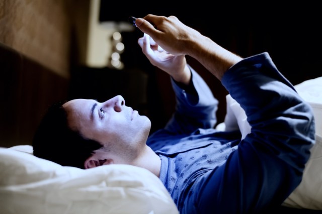 man using his mobile phone in the bed