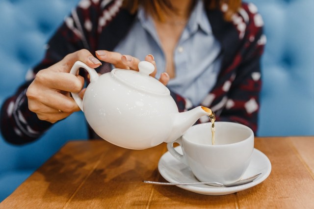 person pours tea from a kettle close up shot